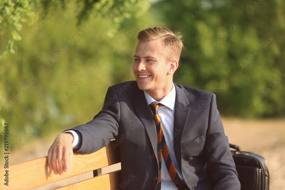 Young man in formal clothes resting in park on sunny day