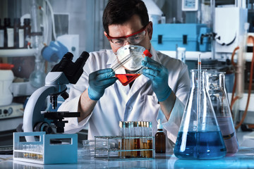 lab technician holding tissue culture flask in the genetic laboratory / scientist working with a flask of human cell culture in the lab