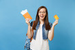 © ViDi Studio - Young shocked excited woman student with backpack spread hands holding passport boarding pass ticket credit card isolated on blue background. Education in university college abroad. Air travel flight.