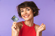 Smiling Pretty brunette woman holding credit card while rejoices