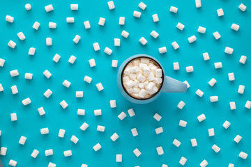 Wall Mural - Cup of coffee with Marshmallow on blue background. Concept winter comfort, morning coffee, warm in middle of cold. Top view. Flat lay.