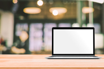 Laptop with blank screen placed on white wooden table in blurred people in coffee shop or restaurant for menu or order receipt from computer