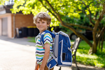 Happy little kid boy with glasses and backpack or satchel on his first day to school or nursery. Child outdoors on warm sunny day, Back to school concept: