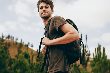 man walking through a forest wearing a backpack.