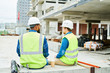 © Seventyfour - Back view portrait of two workers wearing hardhats  chatting while enjoying coffee break on construction site