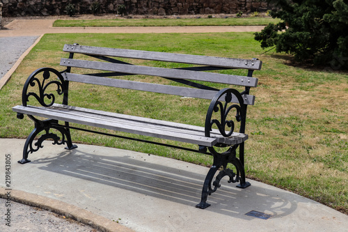 Rustic Park Bench With Wrought Iron Frame Sitting On Concrete With