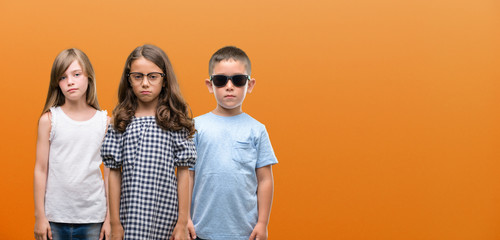 Sticker - Group of boy and girls kids over orange background with a confident expression on smart face thinking serious