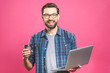 © denis_vermenko - Confident business expert. Confident young handsome man with coffee in shirt holding laptop and smiling while standing against pink background