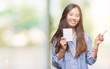 © Krakenimages.com - Young asian woman holding notebook over isolated background very happy pointing with hand and finger to the side