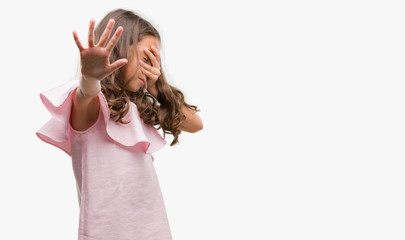 Sticker - Brunette hispanic girl wearing pink dress covering eyes with hands and doing stop gesture with sad and fear expression. Embarrassed and negative concept.