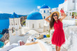 © Maridav - Santorini tourist girl on cruise holiday taking selfie photo with phone at famous three domes church, European tourism attraction in Greece. Asian woman on vacation.