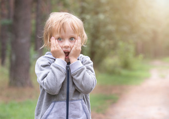 cute boy surprised, emotions and joy. sunny day in the forest and in the park