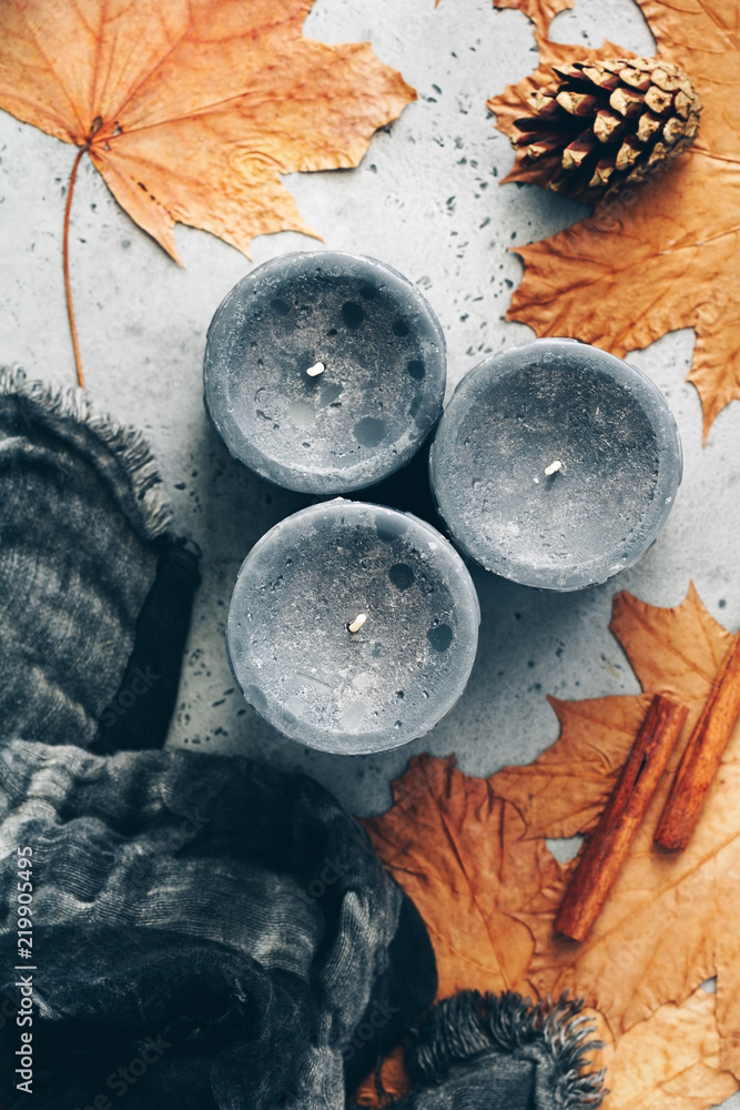 Top view of autumn still life on a grey concrete background. Maple leaves, black aromatic candles and warm scarf. - obrazy, fototapety, plakaty 