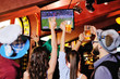 © Evgeniy Kalinovskiy - group or company of young people friends in Bavarian caps - guys and girls watching football on TV in a sports bar holding glasses with beer. Celebration of the Oktoberfest festival