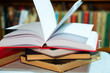 © nagornyi - Open book, stack of hardback books on table. Top view.