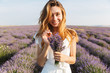 © Drobot Dean - Portrait of cheerful pretty woman in dress holding bunch of flowers, while walking outdoor through lavender field in summer