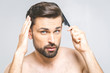 © denis_vermenko - Portrait of handsome young man combing his hair in bathroom. Isolated over grey background.