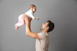 © Drobot Dean - Image of happy father man holding his little child in hands, isolated over gray background