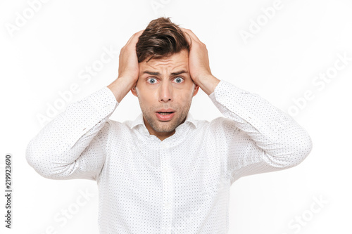 Fotografía Portrait of irritated disappointed man 20s grabbing his head and expressing problem, isolated over white background