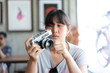 © No-Te - A hipster teenager is taking a film camera in the cafe.
