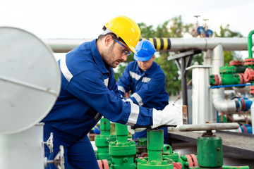 Wall Mural - Two petrochemical workers inspecting pressure valves on a fuel tank