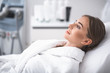 © Yakobchuk Olena - Resting before procedure. Side view of serene lovely girl in white soft bathrobe. Isolated on blurred background