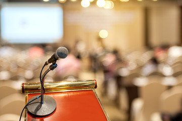 Microphone at the speech podium on blurred conference hall or seminar room background