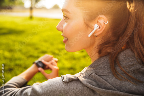 Fotomural Portrait of beautiful sporty woman 20s in sportswear using smartwatch and wirele