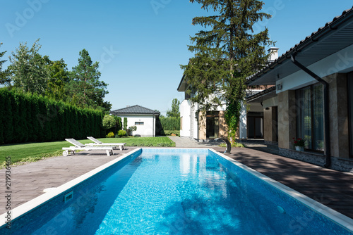 Plakat widok na dom, ogród i basen z leżakami do relaksu