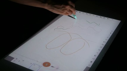 Woman using interactive touchscreen projector display for drawing at modern technology show. Future and entertainment concept