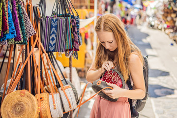 Shopping on Bali. Young woman chooses Famous Balinese rattan eco bags in a local souvenir market in Bali, Indonesia