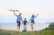 © Pixel-Shot - Happy family flying kite near sea