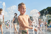 Little Boy Bathes And Splashes In City Fountain