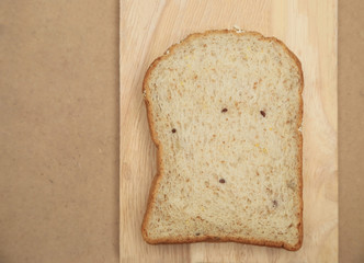 Whole grain bread on wood plate and brown texture background with space for text.