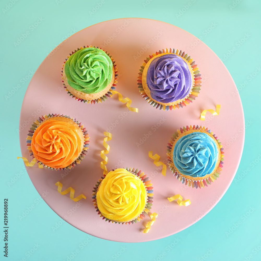 Stand with delicious birthday cupcakes on color background