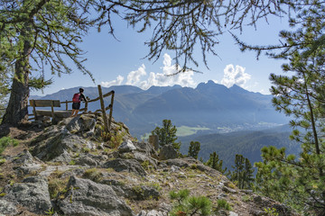 Wall Mural - senior woman, taking a break from her Mountainbike trip and looking over the valley of upper Engadin above Celerina and Saint Moritz, Graubuenden, Switzerland