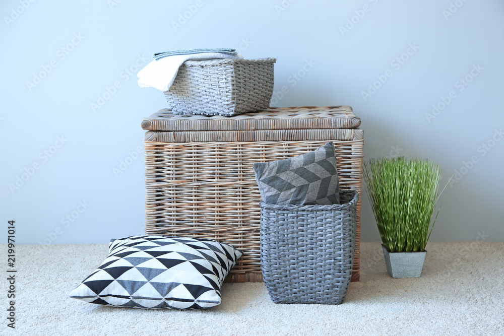Soft pillows with wicker baskets near light wall indoors