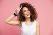 © opolja - Image of happy young woman standing isolated over pink background showing peace gesture. Looking camera