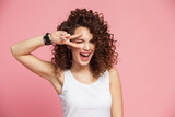Image of happy young woman standing isolated over pink background showing peace gesture. Looking camera