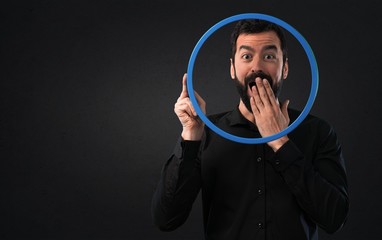 Wall Mural - Handsome man with beard looking through an circle frame on black background