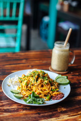 Healthy Vegetarian vegan menu Pad Thai, stir-fried rice noodles, is one of Thailand's national main dish and banana smoothies on wooden table