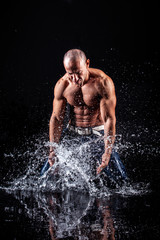 Poster - very muscular handsome athletic man striking with a hand on water