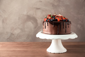 Fresh delicious homemade chocolate cake with berries on table against color background. Space for text