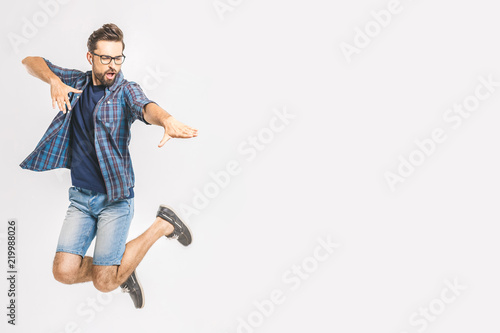 Happy excited cheerful young man jumping and celebrating success isolated on a w Poster Mural XXL