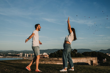 .Young and beautiful couple in love enjoying an afternoon outdoors in Gijón, northern Spain. A funny couple throwing holi powder and staining many colors. Lifestyle..