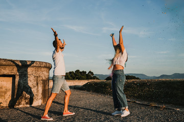 .Young and beautiful couple in love enjoying an afternoon outdoors in Gijón, northern Spain. A funny couple throwing holi powder and staining many colors. Lifestyle..