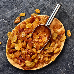 Wall Mural - Yellow big raisins on black concrete background. Top view of dried grapes.