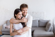 © fizkes - Portrait of happy young couple hugging looking in distance thinking about future family together, smiling boyfriend embracing girlfriend holding her in his arms dreaming about new beginning