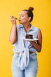 Young pretty woman in shirt happily eating chocolate cake over yellow background isolated. Plus size model