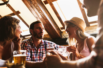 Young cheerful people in the beer pub drinking and having good time. Friendship concept with young people enjoying time together and having genuine fun at cool vintage pub 